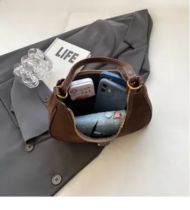 Spacious interior of brown suede hobo bag holding a phone, umbrella and daily essentials