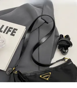 Detail of the high-quality black faux leather underarm bag with gold metal logo plaque
