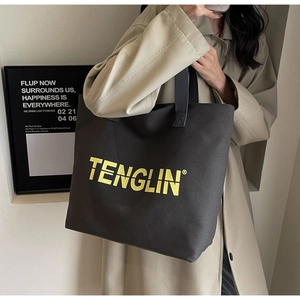 Detail of black canvas tote bag with yellow logo showing large capacity for daily commute