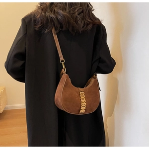 Detail of dark brown suede hobo bag with gold COCREONE letters on model shoulder