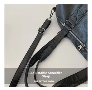 Détail de la bandoulière réglable en cuir noir avec boucle et crochets argentés
