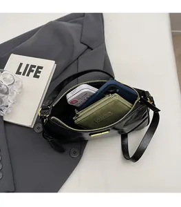 Detail of black patent leather underarm bag showing spacious interior and golden zipper
