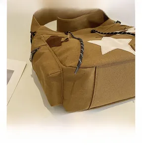 Detail of khaki canvas tote featuring star patch, braided drawstring and metal zipper