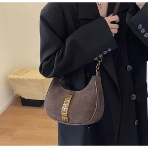 Close-up of brown suede hobo bag featuring gold metal COCREONE letters and zipper closure