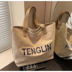 Detail of a large beige canvas tote bag with TENGLIN lettering in a lifestyle setting