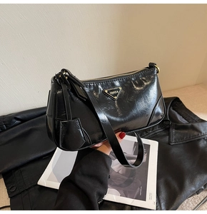 Detail of glossy black wrinkled leather texture and triangle logo on underarm bag