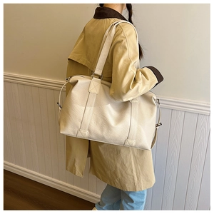 Détail des poignées cousues en croix et ferrures sur un sac cabas blanc crème