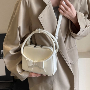 Cream white crossbody bag with stylish bow accent and unique round handle detail
