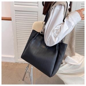 Detail of black tote bag featuring diamond quilted texture and fashion brand label