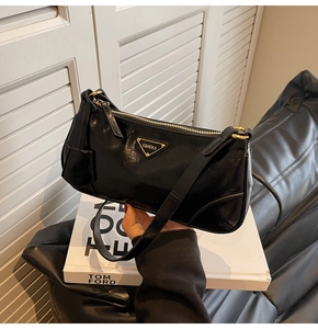 Close-up of black glossy leather hobo bag with triangle logo and gold zipper detail