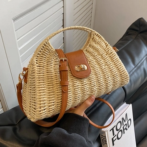 Elegant woven straw handbag with brown leather flap and gold lock shown in hand