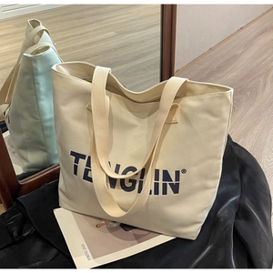 Detail of high-capacity canvas tote bag with brand logo and wide shoulder straps