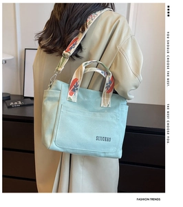 Detailed view of mint green canvas tote bag with jacquard webbing strap on a model