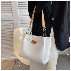 Detail view of white quilted tote bag with fashion tag and chain leather straps