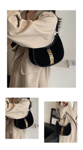 Detail of black suede crescent bag featuring a prominent gold COCREONE metallic logo