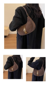 Detail of dark brown suede hobo bag with gold metal logo lettering and vintage texture