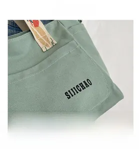 Detail view of mint green canvas tote bag featuring jacquard straps and exterior pocket