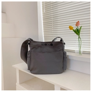 Detail of grey canvas crossbody bag with side pockets and durable stitching for daily use