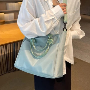Mint green nylon tote bag for women with wide shoulder strap in a cozy cafe setting