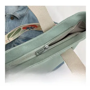 Detail of silver smooth metal zipper closure and patterned strap on canvas tote bag