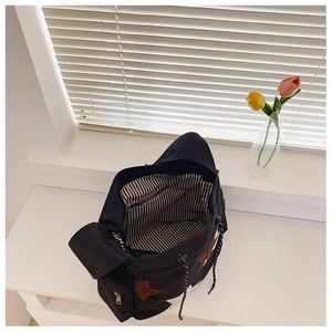 Detail view of large black canvas bag showing striped lining and inner zipper pocket