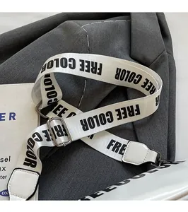 Detail of adjustable white fabric crossbody strap with black FREE COLOR text and metal buckle