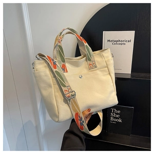 Detail view of beige canvas tote with floral embroidered straps and magnetic pocket