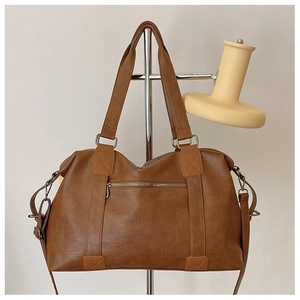 Détail du sac cabas marron montrant la texture grainée et la poche zippée en métal