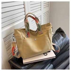 Detail of canvas tote bag showing colorful printed strap and metal snap button pocket