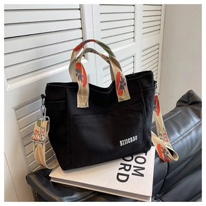Close-up of black canvas tote bag with floral pattern strap and SIJICHAO logo detail