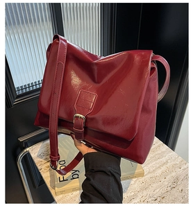 Detail of burgundy vintage tote bag showing glossy leather texture and metal buckle