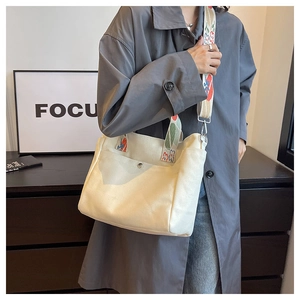 Detailed shot of white canvas tote bag with decorative embroidered wide crossbody strap