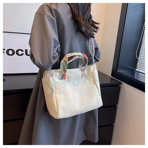 Detail of cream canvas tote bag with ethnic print handles and crossbody strap