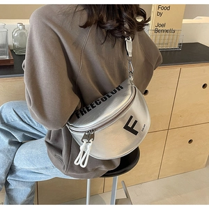 Detail view of silver metallic crossbody bag with black letter print and rope zippers