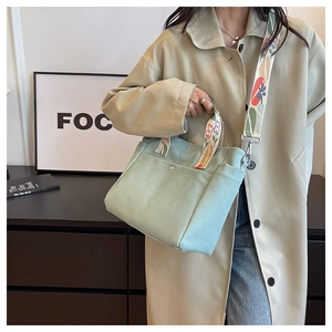 Detail of mint green canvas tote with floral embroidery strap and front pocket detail