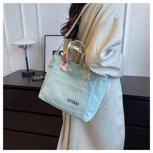 Detail of mint canvas tote bag with ethnic jacquard strap and embroidered logo