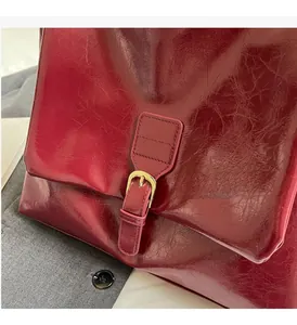 Close-up of wine red oil wax leather tote featuring shiny gold hardware buckle detail