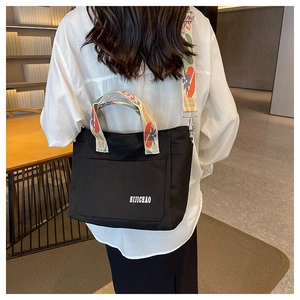 Detail of black canvas tote with floral straps and large front pocket for daily use