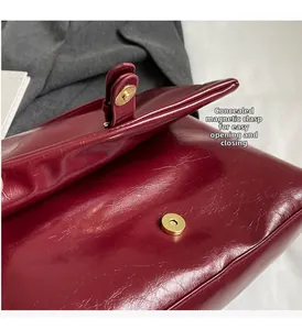 Detail view of the hidden magnetic closure and golden hardware on a burgundy tote bag