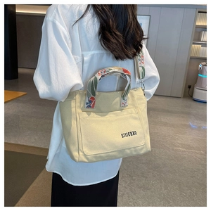 Detail of beige canvas tote bag with floral strap and front pocket for daily commute