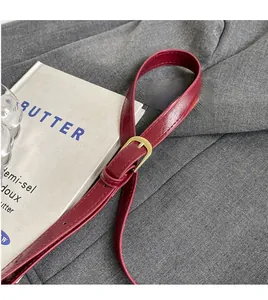 Detail of adjustable wine red PU leather shoulder strap with gold metal buckle hardware