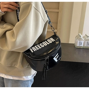 Close-up of the black semi-circle crossbody bag featuring wide branded straps and dual zippers