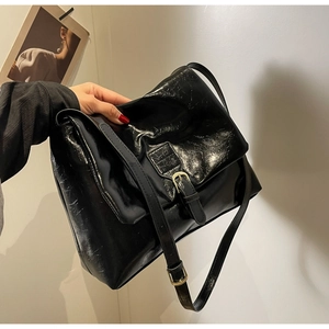 Detail of vintage black tote bag featuring glossy wax texture and adjustable gold buckle