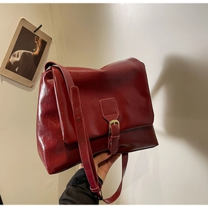 Detailed view of the dark red crinkled glossy leather tote bag with golden buckle hardware