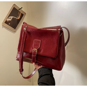 Detail of reddish-brown crossbody tote bag with glossy oil wax leather texture and buckle