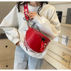 Close-up of red leather chest bag with a sporty wide strap shown on a model
