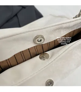 Detail view of the silver magnetic closure and brown striped lining on the white tote bag