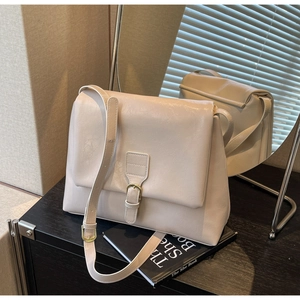 Detail view of cream tote bag with fine leather texture and gold metallic buckle hardware