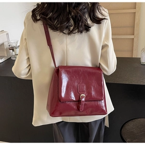 Rear view of a burgundy leather tote bag styled with a beige blazer for a chic look