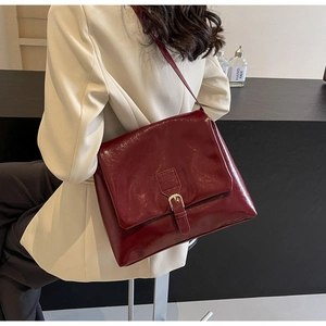 Detail of burgundy vintage oil wax leather shoulder bag with metallic buckle closure